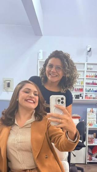 Cliente e profissional sorrindo no espelho do Studio Camarim